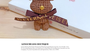 Close-up of brown resin bear keychain with knitted texture and gold-lettered love ribbon