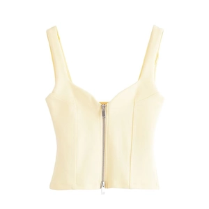 Close-up of pale yellow cropped vest featuring a front metal zipper and wide straps