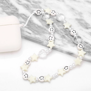 Beaded phone charm with white smiley faces, stars, hearts and pearls on marble background