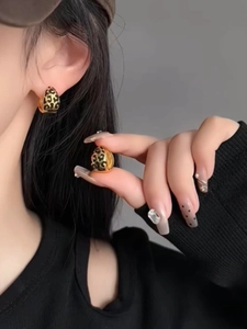 Close-up of small golden hoop earrings with leopard print pattern worn by model