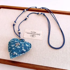 Collier avec pendentif cœur en denim bleu et croix argentée sur cordon tressé