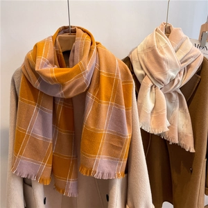 Detail showing soft cashmere-like scarves with fringe and plaid pattern on winter coats