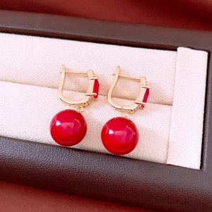 Macro detail of 18K gold plated drop earrings with red agate beads and zircon accents