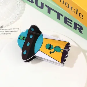 Detailed view of an acrylic UFO hair claw clip with colorful aliens on a stylish tray