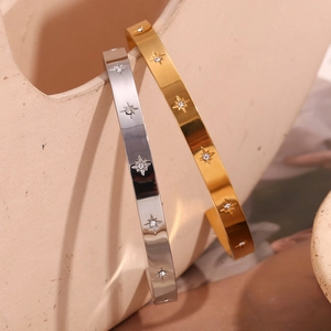 Detail of gold and silver open bangles featuring North Star design with white cubic zirconia