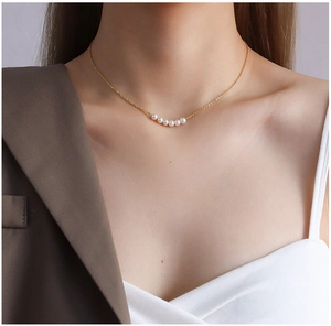 Close-up of 18K gold plated titanium necklace with five pearls worn on a model's neck