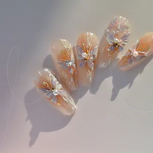 Detail of shimmering butterfly nail charms with pearls and rhinestones on soft pink nails