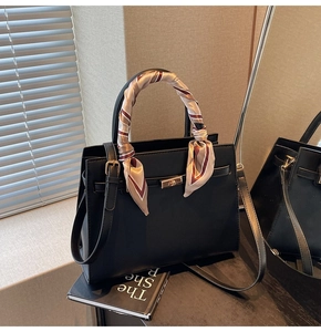 Detail of black faux leather handbag with silk scarf handle and metal turn-lock closure