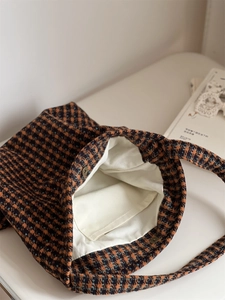 Detail view of houndstooth tote bag featuring fabric lining and magnetic snap closure