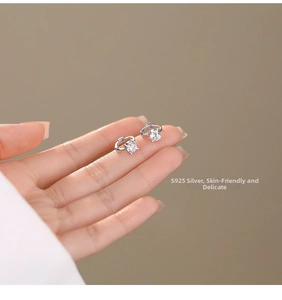 Close-up of minimalist S925 silver hoop earrings with square zircon held by fingertips