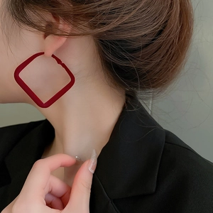 Primo piano di una modella con orecchini geometrici rossi per look festivi natalizi