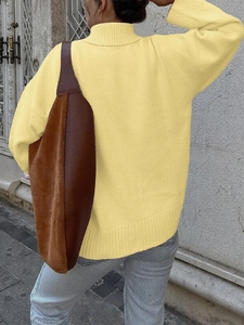 Dettaglio maglione in maglia gialla con bordo a costine e vestibilità comoda sulla modella