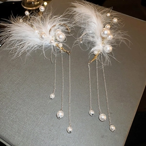 Detail of white feather and pearl tassel ear cuff with golden metallic fringe chains