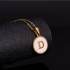 Macro detail of 18K gold stainless steel necklace with pink shell and letter D pendant
