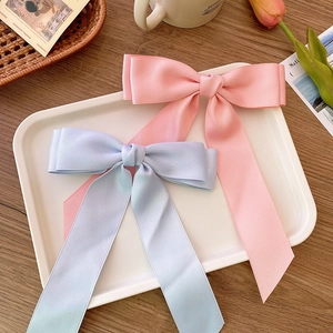 Pink and blue satin balletcore bow hair clips with long streamers on a wooden table