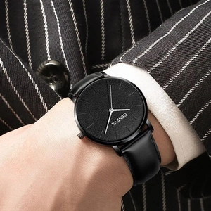 Detail of minimalist black quartz watch with leather strap on a navy suit sleeve