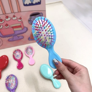 Close-up of mini massage hairbrush with colorful bristles and compact handheld design