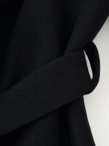 Vue détaillée du passant de ceinture et de la texture du long manteau noir en laine