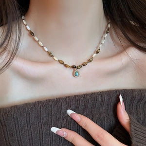 Detail view of tiger eye beads and turquoise pendant on model's neck for a vintage look