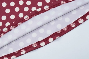 Close-up of classic white polka dot print on wine red fabric with neat edge stitching