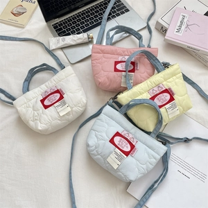 Dettaglio delle mini borse tote con trapuntatura a cuore in quattro colori pastello