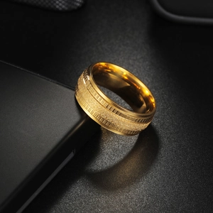Golden embossed matte wedding ring for men with polished edges on a dark surface