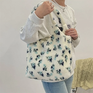 Plush white fleece tote bag with blue floral patterns and colorful side label