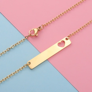 Macro detail of gold bar pendant with heart cutout on a delicate O-chain necklace