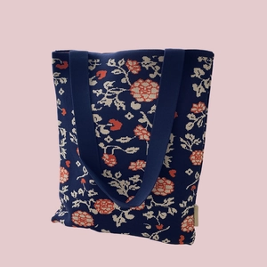Detailed close-up of dark blue knit tote bag featuring beige and orange floral patterns