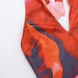 Detailed close-up of deep V-neckline on a silky orange abstract floral print dress