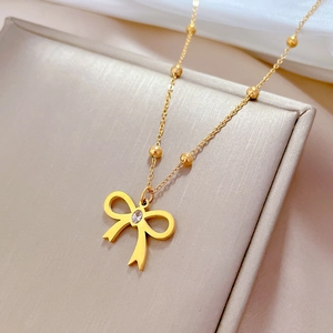 Detailed view of a gold-plated bow necklace with a zircon center in a jewelry box