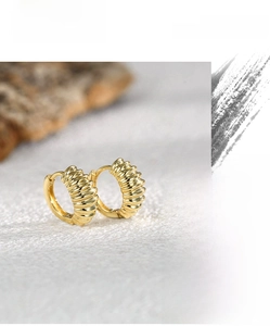 Macro detail of gold-plated croissant hoop earrings with a textured spiral vintage design
