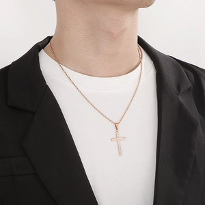 Close-up of a gold stainless steel cross necklace with diamonds worn by a male model