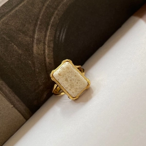 Retro gold rectangle ring with cream marble stone on a minimalist split-tone background