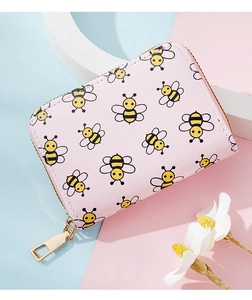 Detailed view of pink bee print card holder with gold zipper on pastel background