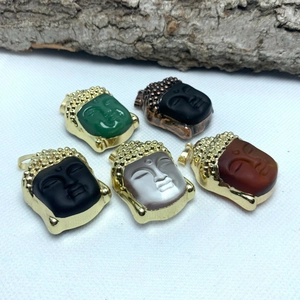 Macro view of crystal Buddha head pendants with gold metal edges in various colors