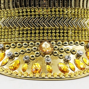 Macro detail of luxury gold captain hat with rhinestones, bead chains and amber gemstones