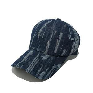 Detailed view of distressed dark blue denim baseball cap with vintage white frayed texture