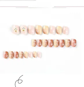 Dettaglio di unghie finte con orsetti marroni e design sfumato con nuvole rosa