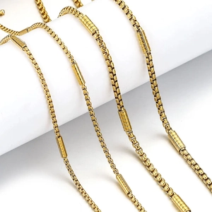 Golden stainless steel Venetian box chain necklaces with cylindrical charms on white background