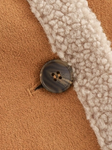 Detail aus Wollmischgewebe und dunklem Marmorknopf am braunen Pelzmantel