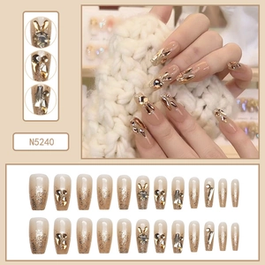Detailed view of long coffin press-on nails with champagne gradient and golden rabbit charms