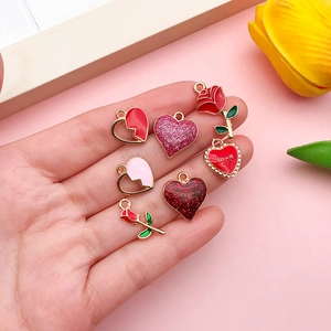 Macro shot of colorful enamel heart charms and rose pendants held in hand