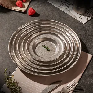 Stack of vintage stainless steel deep pasta plates in multiple sizes on dark stone table