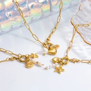 Detailed close-up of a gold necklace featuring pearl, starfish, shell, and heart charms