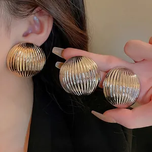 Textured gold and silver chunky round hoop earrings with vertical striped metallic finish