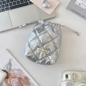 Macro detail of silver quilted PU leather drawstring pouch on a lifestyle desk setup