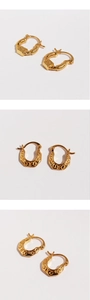 Macro detail of golden U-shaped earrings with embossed geometric texture and hinge closure
