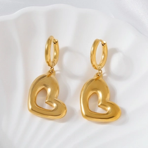 Boucles d'oreilles cœur évidé dorées minimalistes sur un plateau coquillage blanc