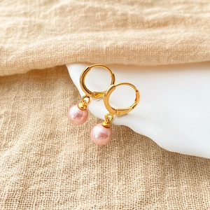 Detail of pink pearl drop earrings with 18K gold plated hoops on a ceramic dish